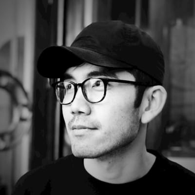 Black and white headshot of Nan Yu, in a black cap and glasses